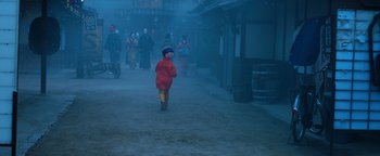Movie still from “Prisoners of the Ghostland” (2021), directed by Sion Sono – A little boy walking down a street in the rain; Extreme Wide shot, High angle
