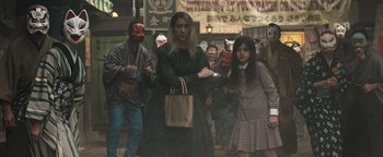 Movie still from “Prisoners of the Ghostland” (2021), directed by Sion Sono – A group of people dressed in costumes walking down a street; Medium shot, High angle