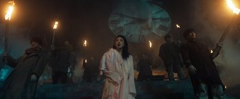 Movie still from “Prisoners of the Ghostland” (2021), directed by Sion Sono – A woman standing in front of a large clock; Wide shot, Low angle