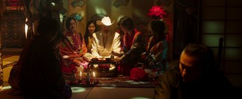Movie still from “Prisoners of the Ghostland” (2021), directed by Sion Sono – A group of people sitting around a table with candles on it; Medium shot, High angle