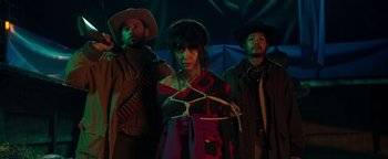 Movie still from “Prisoners of the Ghostland” (2021), directed by Sion Sono – A group of people standing next to each other in a dark room; Medium shot, Low angle