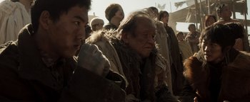 Movie still from “Prisoners of the Ghostland” (2021), directed by Sion Sono – An old man in a crowd of people; Medium shot, Low angle