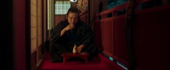 Movie still from “Prisoners of the Ghostland” (2021), directed by Sion Sono – A man sitting on the ground with a tray of food; Medium shot, Low angle