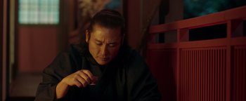 Movie still from “Prisoners of the Ghostland” (2021), directed by Sion Sono – A person sitting down looking down at something; Close Up shot, Low angle