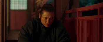 Movie still from “Prisoners of the Ghostland” (2021), directed by Sion Sono – A man in a black robe is looking down; Close Up shot, Low angle