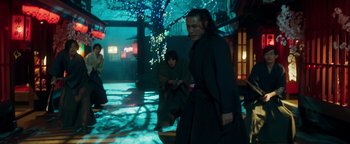 Movie still from “Prisoners of the Ghostland” (2021), directed by Sion Sono – A couple of people that are standing in the dark; Wide shot, Low angle