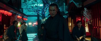 Movie still from “Prisoners of the Ghostland” (2021), directed by Sion Sono – A man wearing a black robe standing in front of a tree; Medium shot, Low angle
