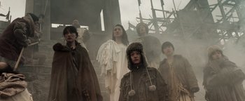 Movie still from “Prisoners of the Ghostland” (2021), directed by Sion Sono – A group of people standing on top of a building; Medium shot, Low angle