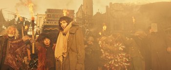 Movie still from “Prisoners of the Ghostland” (2021), directed by Sion Sono – A woman standing in front of a pile of trash; Medium shot, Low angle