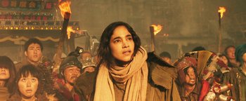 Movie still from “Prisoners of the Ghostland” (2021), directed by Sion Sono – A woman in a crowd of people wearing a scarf; Close Up shot, Low angle