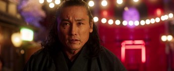 Movie still from “Prisoners of the Ghostland” (2021), directed by Sion Sono – A man with long black hair and a scar on his face; Close Up shot, Low angle