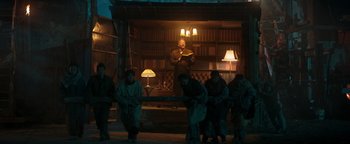 Movie still from “Prisoners of the Ghostland” (2021), directed by Sion Sono – A group of people standing around a room; Wide shot, Low angle