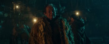 Movie still from “Prisoners of the Ghostland” (2021), directed by Sion Sono – An old man wearing a fur coat in the dark; Close Up shot, Low angle