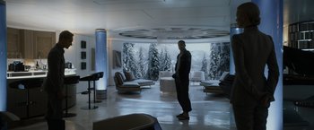 Movie still from “Prometheus” (2012), directed by Ridley Scott – A man standing in a living room next to trees; Wide shot, Over the shoulder angle
