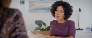 Movie still from “Puppy Love” (2023), directed by Richard Alan Reid – A woman sitting at a table using a computer; Medium shot, Over the shoulder angle