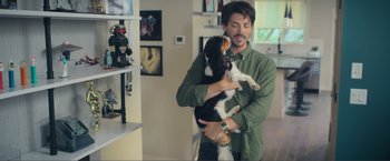 Movie still from “Puppy Love” (2023), directed by Richard Alan Reid – A man holding a black and white dog in his arms; Medium shot, Over the shoulder angle