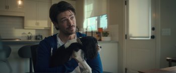 Movie still from “Puppy Love” (2023), directed by Richard Alan Reid – A man holding a black and white dog in his arms; Close Up shot, Over the shoulder angle