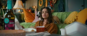 Movie still from “Puppy Love” (2023), directed by Richard Alan Reid – A woman sitting on a couch next to a dog; Medium shot, Over the shoulder angle