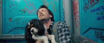 Movie still from “Puppy Love” (2023), directed by Richard Alan Reid – A man holding a black and white dog in his arms; Close Up shot, Low angle