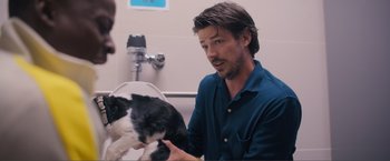 Movie still from “Puppy Love” (2023), directed by Richard Alan Reid – A man sitting in front of a cat in a bathroom; Medium shot, Over the shoulder angle