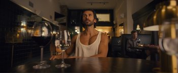 Movie still from “Puppy Love” (2023), directed by Richard Alan Reid – A man sitting at a table with a glass of wine; Medium shot, Low angle