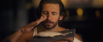 Movie still from “Puppy Love” (2023), directed by Richard Alan Reid – A bearded man holding a fish in front of his face; Close Up shot, Over the shoulder angle