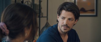 Movie still from “Puppy Love” (2023), directed by Richard Alan Reid – A person sitting in a room; Close Up shot, Over the shoulder angle