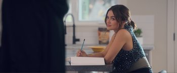 Movie still from “Puppy Love” (2023), directed by Richard Alan Reid – A beautiful young lady sitting at a counter writing in a notebook; Close Up shot, Over the shoulder angle