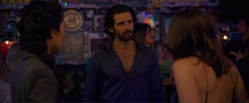 Movie still from “Puppy Love” (2023), directed by Richard Alan Reid – A man with long black hair wearing a black shirt; Medium shot, Over the shoulder angle