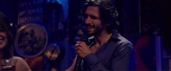 Movie still from “Puppy Love” (2023), directed by Richard Alan Reid – A man holding a microphone in his hand; Close Up shot, Over the shoulder angle