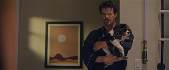 Movie still from “Puppy Love” (2023), directed by Richard Alan Reid – A man holding a black and white dog in his arms; Medium shot, Over the shoulder angle
