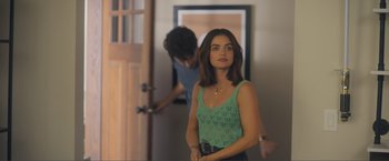 Movie still from “Puppy Love” (2023), directed by Richard Alan Reid – A woman standing in a room holding a camera; Medium shot, Over the shoulder angle