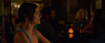 Movie still from “Puppy Love” (2023), directed by Richard Alan Reid – A woman smiling at a party in the dark; Close Up shot, Over the shoulder angle