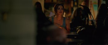 Movie still from “Puppy Love” (2023), directed by Richard Alan Reid – A woman sitting at a table in front of other people; Close Up shot, Over the shoulder angle