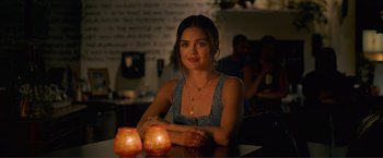 Movie still from “Puppy Love” (2023), directed by Richard Alan Reid – A beautiful young lady sitting at a table with candles; Close Up shot, Over the shoulder angle