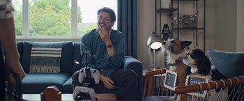Movie still from “Puppy Love” (2023), directed by Richard Alan Reid – A man sitting in a chair next to a cat; Medium shot, Over the shoulder angle