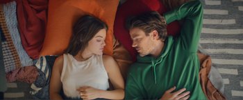 Movie still from “Puppy Love” (2023), directed by Richard Alan Reid – A man and a woman laying in bed together; Medium shot, Overhead angle