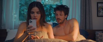 Movie still from “Puppy Love” (2023), directed by Richard Alan Reid – A man and a woman sitting on a bed looking at a cell phone; Medium shot, Over the shoulder angle