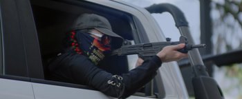 Movie still from “Pursuit” (2022), directed by Brian Skiba – A person in a car with a gun in his hand; Close Up shot, Low angle