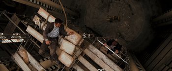Movie still from “Quantum of Solace” (2008), directed by Marc Forster – A man sitting on top of a set of stairs; Wide shot, Overhead angle