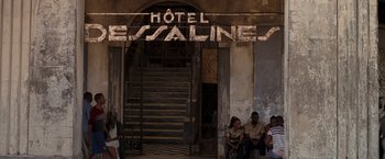 Movie still from “Quantum of Solace” (2008), directed by Marc Forster – A group of people sitting in front of an old building; Extreme Wide shot, Low angle