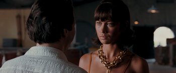 Movie still from “Quantum of Solace” (2008), directed by Marc Forster – A woman wearing a gold chain around her neck; Close Up shot, Over the shoulder angle