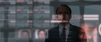 Movie still from “Quantum of Solace” (2008), directed by Marc Forster – A man wearing a suit and tie standing in front of a window; Close Up shot, Low angle