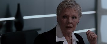 Movie still from “Quantum of Solace” (2008), directed by Marc Forster – An older woman with short hair wearing a black jacket; Close Up shot, Low angle