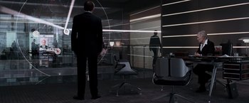 Movie still from “Quantum of Solace” (2008), directed by Marc Forster – A man in a suit standing in front of a glass wall; Wide shot, Over the shoulder angle