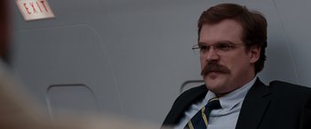 Movie still from “Quantum of Solace” (2008), directed by Marc Forster – A man in a suit and tie with a mustache; Close Up shot, Over the shoulder angle