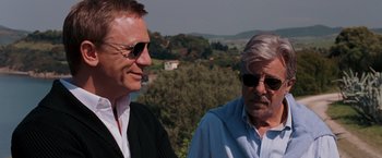 Movie still from “Quantum of Solace” (2008), directed by Marc Forster – A man and an older man standing next to each other; Close Up shot, Over the shoulder angle