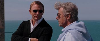 Movie still from “Quantum of Solace” (2008), directed by Marc Forster – Two men standing next to each other near the ocean; Close Up shot, Over the shoulder angle