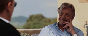 Movie still from “Quantum of Solace” (2008), directed by Marc Forster – An older man sitting on top of an outdoor chair; Close Up shot, Over the shoulder angle