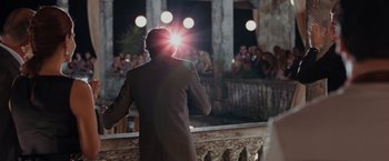 Movie still from “Quantum of Solace” (2008), directed by Marc Forster – A man in a brown jacket is holding a microphone; Wide shot, Over the shoulder angle